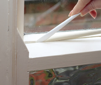 Gapseal being pushed into a sash window gap
